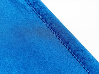 Close-up of durable stitching on a vibrant electric blue fabric, bright energetic natural sunlight, 35mm