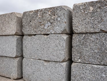 Close-up documentary shot of rough-hewn granite blocks stacked in a Bolivian quarry yard, overcast daylight revealing grain and natural fracture lines, no people, flat natural light