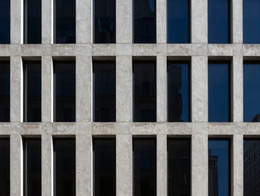 Minimalist modern concrete skyscraper facade in New York, sharp high-contrast afternoon sunlight, deep shadows, architectural crop