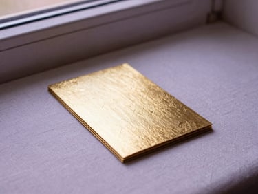 Elegant gold-foiled prayer cards resting on a textured linen surface next to a quiet window