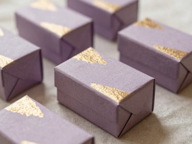 A beautifully arranged gift box with textured paper and gold foil details on a soft linen surface, 35mm