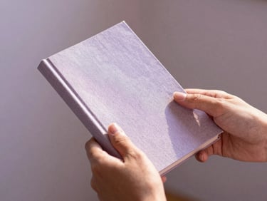 A close-up of hands holding a linen-bound guidebook in soft morning light, shallow depth of field, 35mm