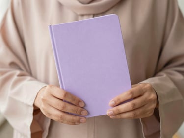 Hands gently holding a minimalist lilac Umrah guidebook, soft natural morning light, shallow depth of field