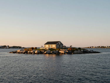 Low-slung stone residence on a private Scandinavian islet, golden hour, calm deep water.