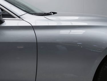 Straight-on documentation shot of a perfectly smooth car panel exterior after dent removal, gloss paint surface reflecting even studio light, no imperfections visible, clinical finish