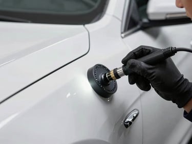 Close-up of a technician's gloved hand pressing a specialized PDR light board against a car panel to reveal a dent, bright even studio lighting, no shadows, straight-on framing