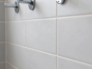 Macro shot of perfectly aligned ceramic tiles in a modern bathroom, clean grout lines, chrome fixtures, sharp focus