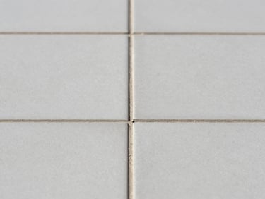 Macro shot of perfectly aligned grey ceramic tiles, razor-thin clean joints, bright natural light, architectural photography.