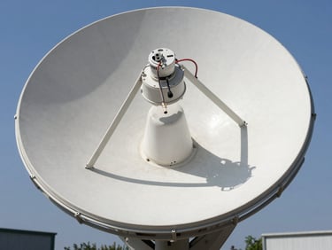 A satellite dish LNB head with coaxial cables connected, sharp focus, bright outdoor daylight.