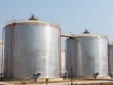 Large-scale chemical storage tanks with safety measures on an agricultural facility, clean daylight, wide environmental shot.