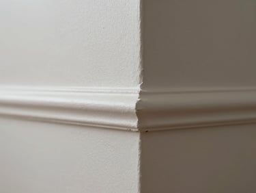 Macro shot of a freshly painted interior wall corner, satin finish catching diffused window light, clean cut-in line where wall meets trim, no brush marks visible