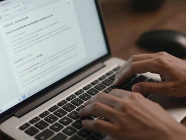 Close-up of hands on a keyboard with a broadcast email draft open on screen, subject line and preview text visible, send schedule panel in view, studio daylight from above, no lifestyle staging