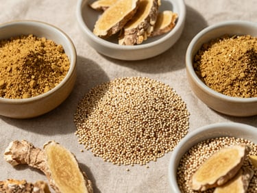 Overhead close-up flat-lay of quinoa grains, dried ginger root pieces and camu camu powder in small ceramic bowls arranged on a rough linen surface, natural north-facing daylight, warm gold and cream tones, no artificial lighting