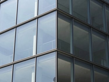 Architectural close-up of a modern frameless glass corner installation, crisp daylight, sharp focus, clean reflections, 35mm lens