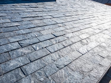 High-angle architectural shot of a clean, finished slate roof under bright daylight, crisp details