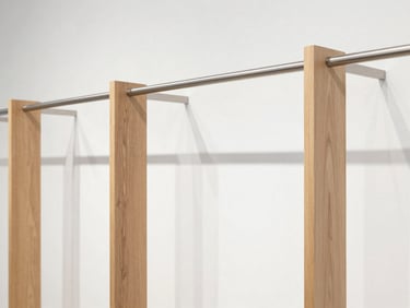 Minimalist lifestyle store interior showing custom apparel racks made of brushed steel and light oak wood, bright lighting
