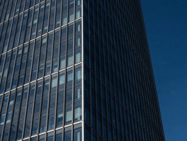 Dramatic architectural photography of a modern glass skyscraper corner reflecting deep midnight blue sky, sharp diagonal lines, high contrast.