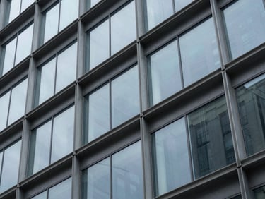 Abstract macro shot of structured steel and glass architectural facade, cool corporate tones, soft overcast light