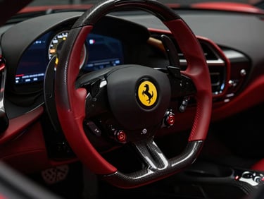 Dramatic close-up of a red Ferrari SF90 Stradale steering wheel with yellow emblem, carbon fiber accents, moody studio lighting, deep shadows, high contrast, 50mm