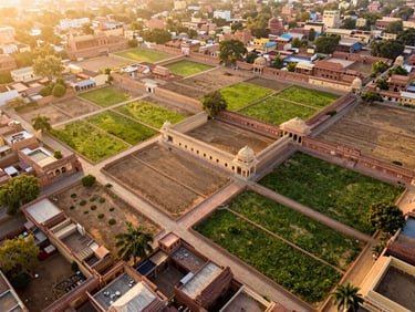 High-resolution drone shot of structured land plots in Jaipur, warm golden-hour sunlight, rich sandstone tones, architectural wide-angle lens