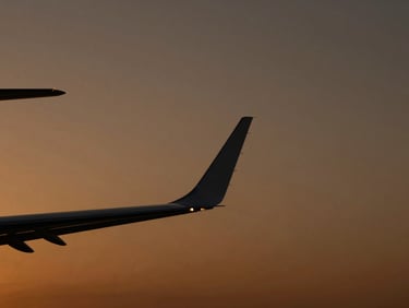 Sleek private jet wingtip silhouetted against a deep amber twilight sky, clean composition, cinematic editorial photography, 35mm.