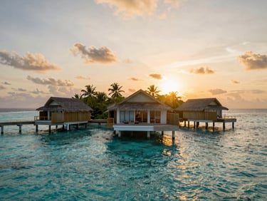 Aerial view of a tiny private tropical island at sunset, glowing villas, deep turquoise reef surrounding the white sand