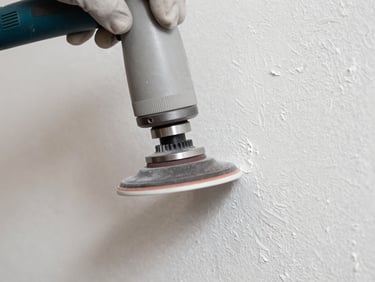 Straight-on macro shot of a dust-free sanding machine head gliding over a pristine, freshly repaired plaster wall, bright natural side-light highlighting the smooth texture, clean workspace.