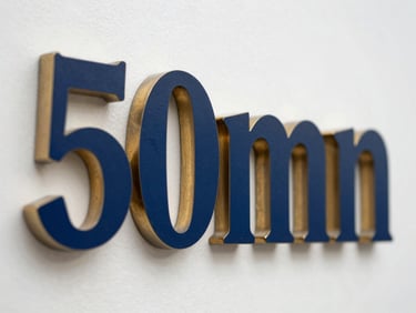 Close-up of a custom-milled metal sign with a deep blue finish, sharp edges, and warm gold accents, studio lighting emphasizing texture, 50mm