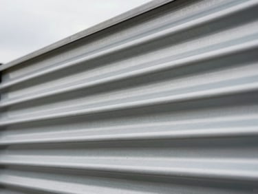 Macro close-up of industrial corrugated steel siding, clean lines, diffused overcast daylight.