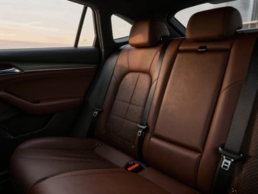 Close-up of a luxury vehicle interior, focusing on leather and carbon fiber textures, low-key dramatic lighting, wide-angle lens.