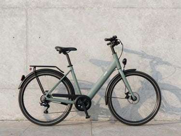 A sleek, modern electric commuter bicycle parked against a minimalist concrete wall in Paris, soft morning light, technical-premium aesthetic, 35mm lens.