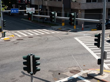 Wide environmental shot of an urban intersection with installed traffic signals and road signage panels, natural daylight, overhead logistics perspective showing order and scale of installed infrastructure