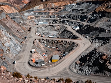 Wide overhead view of a mining site access road and infrastructure in the Peruvian Andes, rugged terrain, midday light, no people, showing scale and order