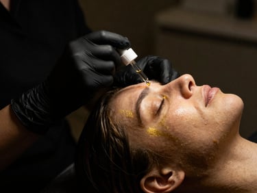 Close-up of a clinical cosmetology facial treatment, hands in black gloves applying serum, dramatic low-key lighting, gold highlights, 35mm