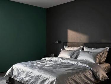 Modern bedroom with clean lines, silver-toned linens, dark charcoal walls, soft twilight architectural lighting casting elegant shadows