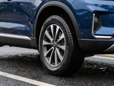 Modern SUV navigating wet road, focus on the tire tread pattern and water dispersion, crisp daylight.
