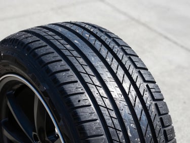 Detailed close-up of a premium passenger car tire on a clean concrete surface, sharp focus on tread patterns.