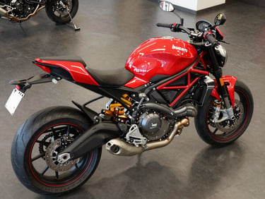 Overhead wide shot of a Ducati Monster 937 on polished showroom floor, red and black bodywork under precision studio strobe, trellis frame and engine fins in sharp detail, no rider