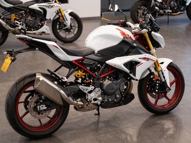 Tight overhead shot of a BMW G 310 R parked on polished gallery floor under controlled strobe, white and red bodywork, alloy wheels sharp in focus, no rider