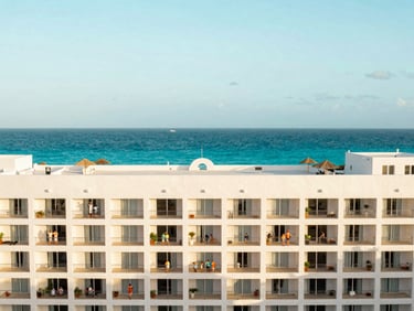 Bright editorial travel photography of a luxury hotel facade in Cancun, turquoise sea in background, golden hour, 35mm lens