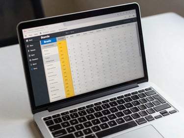 Overhead close-up of a laptop on a clean office desk under neutral daylight, screen displaying a structured time zone comparison interface with Brasília highlighted as the reference column, calendar grid visible in background
