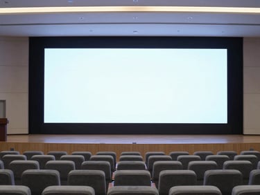 Clean architectural shot of a modern corporate auditorium, empty rows of seating, large crisp display screen illuminated on stage, cool lighting, 35mm
