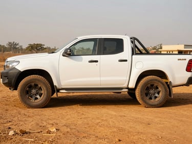 Side view of a rugged white double-cabin pickup truck on the dirt lot, bright Nigerian sun highlighting the clean chassis.