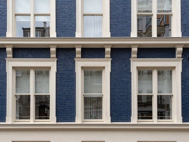 Straight-on architectural photograph of a historic brick apartment building facade with large sash windows, soft overcast daylight, clean lines, sharp focus