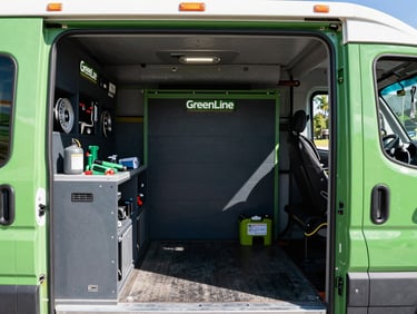 Interior shot of a GreenLine Garage Door's Repairs Team service truck, neatly organized with various garage door parts, tools, and equipment, bright natural daylight, clean green and charcoal tones, sharp focus, 35mm.