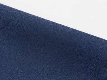 High-magnification macro shot of deep navy dyed acetate tricot fabric, showing detailed fiber weave, clean industrial studio lighting