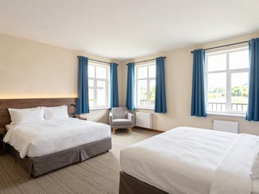 Spacious family connecting hotel rooms with two large beds, bright windows, clean and safe interiors.
