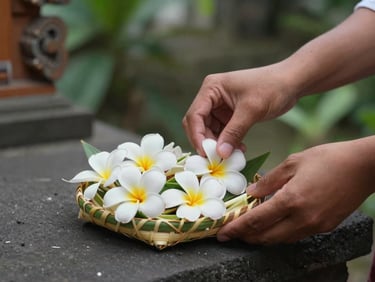 Intimate close-up of a Balinese offering being placed on a temple step, hands arranging frangipani flowers in a woven palm leaf tray, morning light, soft green background, no tourists, natural gesture