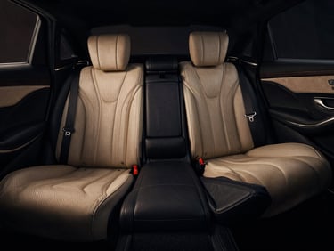 Close-up of a pristine black Mercedes S-Class leather interior, low-key dramatic lighting, champagne-gold accents