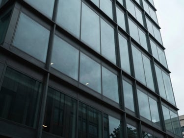 Low-angle shot of a modern corporate building facade with geometric glass patterns, cool overcast daylight, 35mm